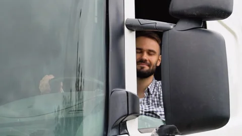 A driver sitting inside the semi-truck while looking at camera through the open Stock Footage 251840251