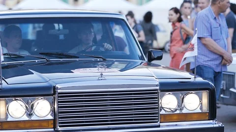 The driver slowly rides with a man on the square in a rare car. Stock Footage 126568790