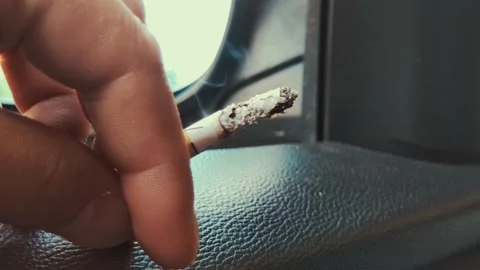 The driver smokes in the car. In the open window of a car, a man puts his hand Stock Footage 220952153