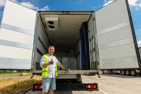 Driver standing near open cargo doors of reefer truck 스톡 사진
