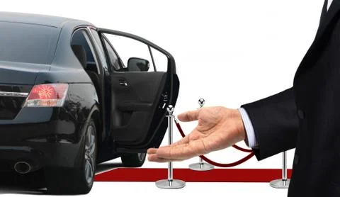 Driver standing with welcome gesture next to limousine Stock Photos
