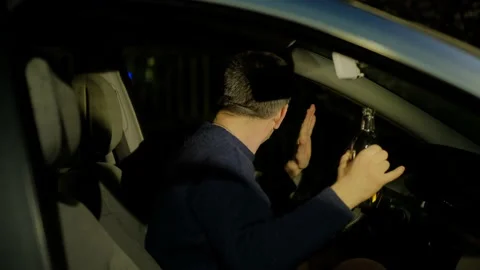 Driver in sweater raises hands with empty alcohol bottle Video stock 155285981
