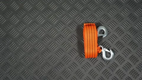 Driver takes orange tow cable laying on black mat in boot of automobile Video stock 149146976