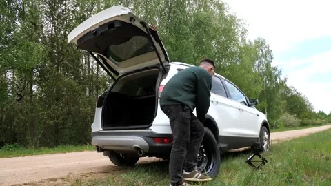 Driver takes out spare tire from the trunk of car. replacing a damaged flat tire Stock Footage 275841782