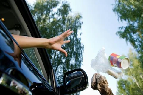Driver throws a handful of garbage accumulated in the car through the open wi Stock Photos
