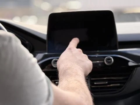 Driver touching central dashboard multimedia screen in car Stock-Fotos
