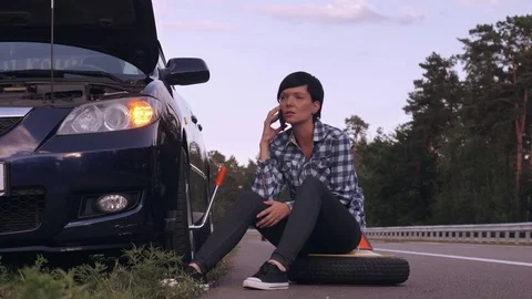 Driver try to change a tire outdoors using smartphone. Stock Footage
