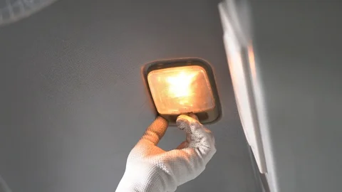 The driver turns on and off the light in the car with a beige ceiling Stock Footage 128696624