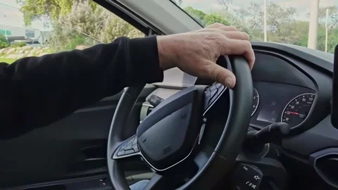 The driver turns the steering wheel with one hand while turning at a roundabout Stock Footage 323389946