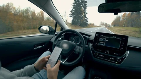 Driver types on a phone while a car goes on autopilot. Automatic, self-driving Stock Footage 120524992