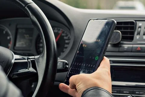 Driver types on smartphone while driving, highlighting the risk and importanc Stock Photos