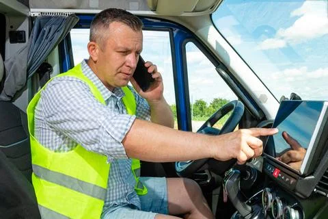 Driver using GPS navigation screen in truck cabin Stockfoto's