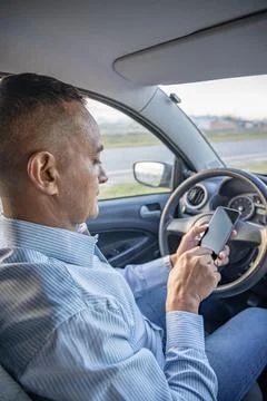 Driver using a mobile phone inside his car. Stock Photos