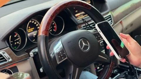 Driver using smartphone in luxury car interior Stock Footage 334091979