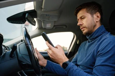 Driver using smartphone in parked car Stock Photos