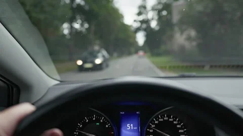 Driver view from car interior on tree lined road with blurred windshield, hand Stock Footage 344773584
