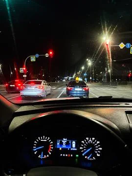 Driver view at night stopped at a red light in city traffic with illuminate.. Stock Photos