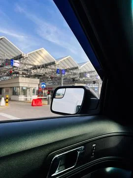 Driver view through car window at a border toll checkpoint with side mirror.. Stock Photos