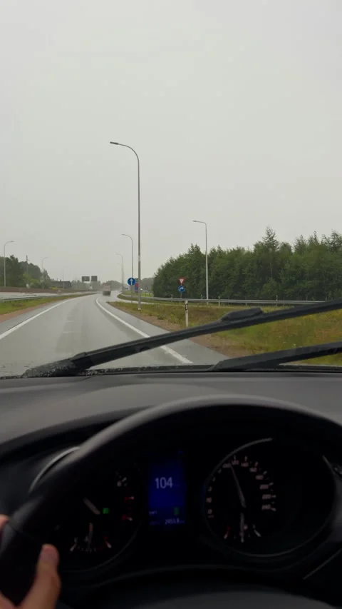 Driver view through rainy windshield on curving highway with wipers and Stock Footage 345452329