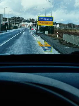 Driver view of wet road approaching a border checkpoint with bright Have a .. Stock Photos