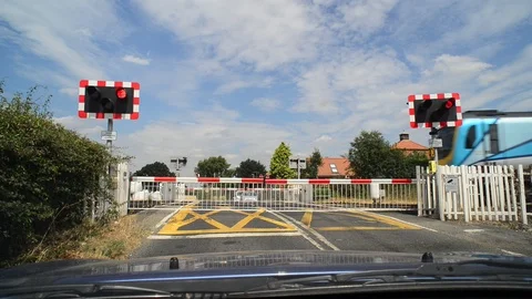 Driver waiting for train to pass at railway level crossing uk Stock Footage 92848070