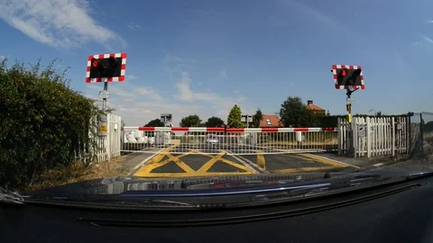 Driver waiting for train to pass at railway level crossing uk Stock Footage 92848345