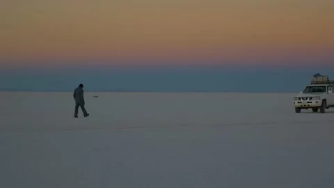 A driver walks to his car at dusk in the Uyuni Desert, Bolivia Stock Footage 237531256