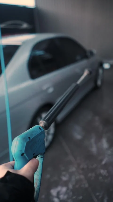 A driver washes a car with water, foam, and wax at a self-service car wash Stockbeeldmateriaal 333595166