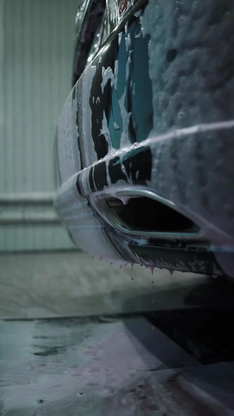 A driver washes a car with water, foam, and wax at a self-service car wash Stockbeeldmateriaal 333595211