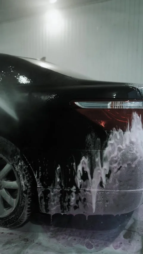 A driver washes a car with water, foam, and wax at a self-service car wash Stockbeeldmateriaal 333595223