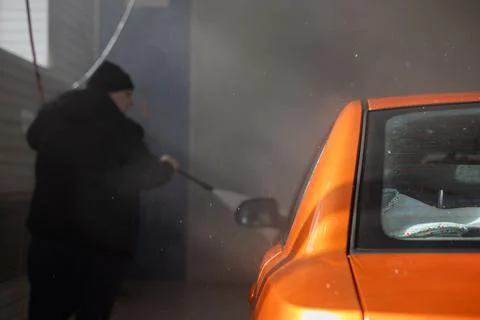 The driver washes his car. Splashes of water fly in all directions. A car in a Stock Photos