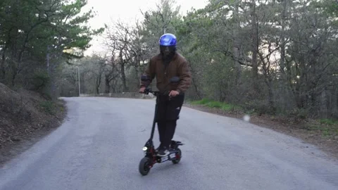 A driver wearing a protective helmet and a powerful electric scooter drives Video stock 153056334
