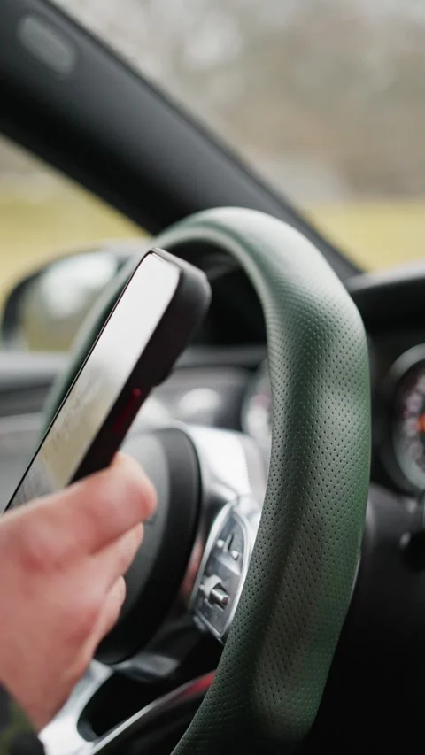 The driver, while driving a car, uses a mobile phone, types text in a chat, and Stock Footage 323308777