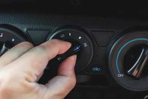 The driver's hand adjusts the switch of the air conditioner. Stock Photos