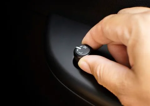 The driver's hand adjusts the wing mirror direction control switch. Stock Photos