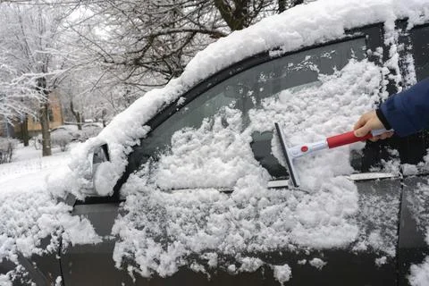 The driver's hand creaning the car from snow in the morning before the journey Foto stock