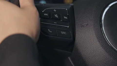 The driver's hand is pressing the answer button on the steering wheel in the car Stock Footage 181344943