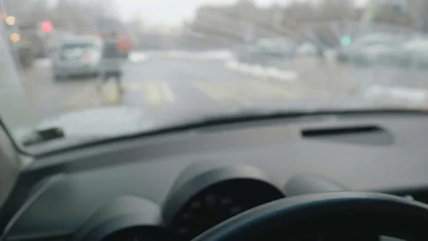 Driver's hands are on steering wheel of car at crossroad. He takes finger nails Stock Footage 124535858