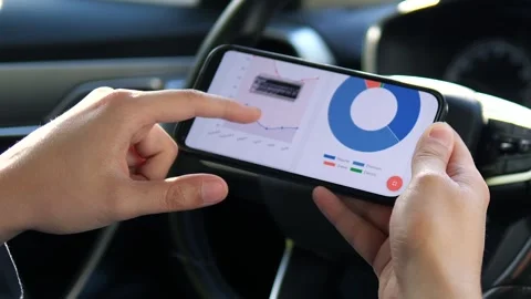 A drivers hands interact with a fuel expense app, tapping on graphs to analyze Stock Footage 315744456