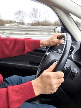 The drivers hands on the steering wheel of a car while driving 写真素材