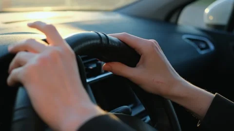 Driver's hands tapping on steering wheel in car while driving Stock Footage 265703470