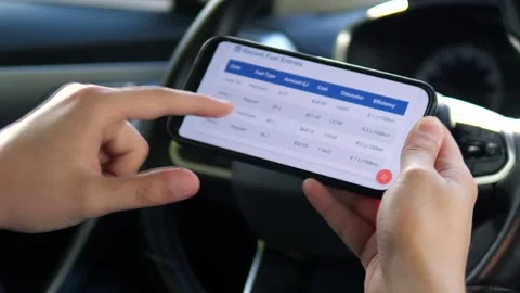 A drivers hands use a fuel cost tracking application on a phone, scrolling 스톡 동영상 316129328