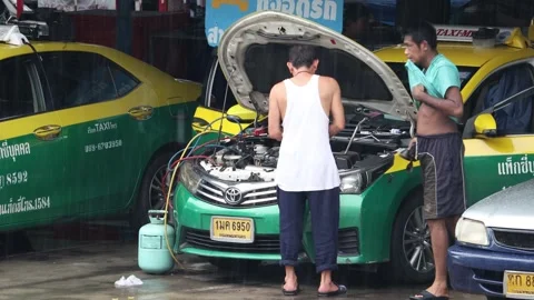 Drivers repairs taxi engine in rainy weather at city taxi station Video stock 310178793