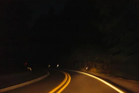 Driver's view of a highway road bend at night with limited visibility Stock Photos