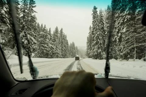 Driver's view through the windscreen of a snowy road and cars driving, a dr.. Stock Photos