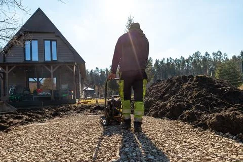 Driveway base compaction beside dark timber A frame house with porch Stock Photos