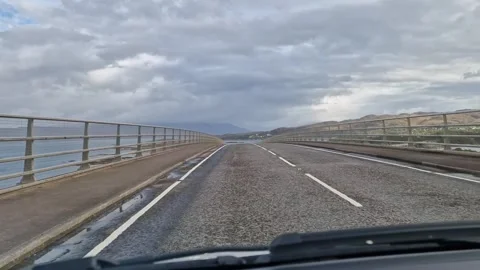 Driving across popular tourist bridge from Isle of Skye in Scotland Stock Footage 293909853