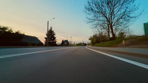 Driving Along Empty Asphalt Road at Sunset With Warm Golden Light and Shadowy Stock Footage 329067391