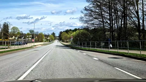 Driving along empty street with bus stop and trees in spring in Smiltene, Latvia Stock Footage 309004388