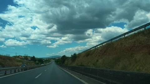 Driving along highway under vast, fluffy clouds. Greece Stock Footage 340638355